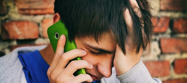 Un adolescent au téléphone, il se prend la tête et a l'air malheureux